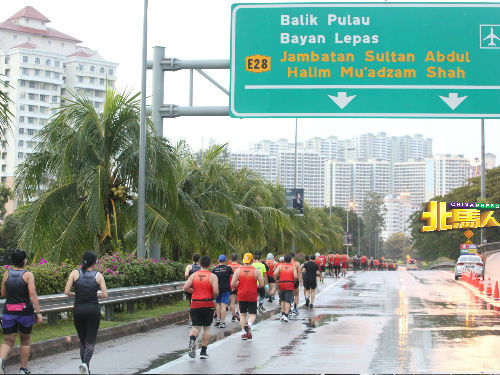槟城大桥国际马拉松赛期间下起大雨又闪电，主办单位被迫取消10公里项目，图为全马拉松及半马拉松跑手在雨中竞跑。