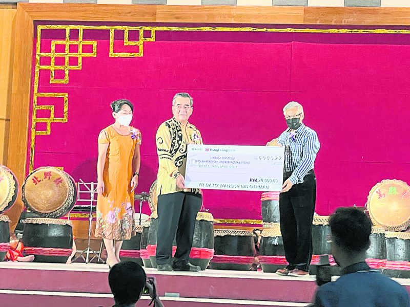 曼梳（右）捐献2万令吉予威南日新国中，充作购买华乐与管弦器材，左2为该校董事长拿督李振兴接领模型支票。
