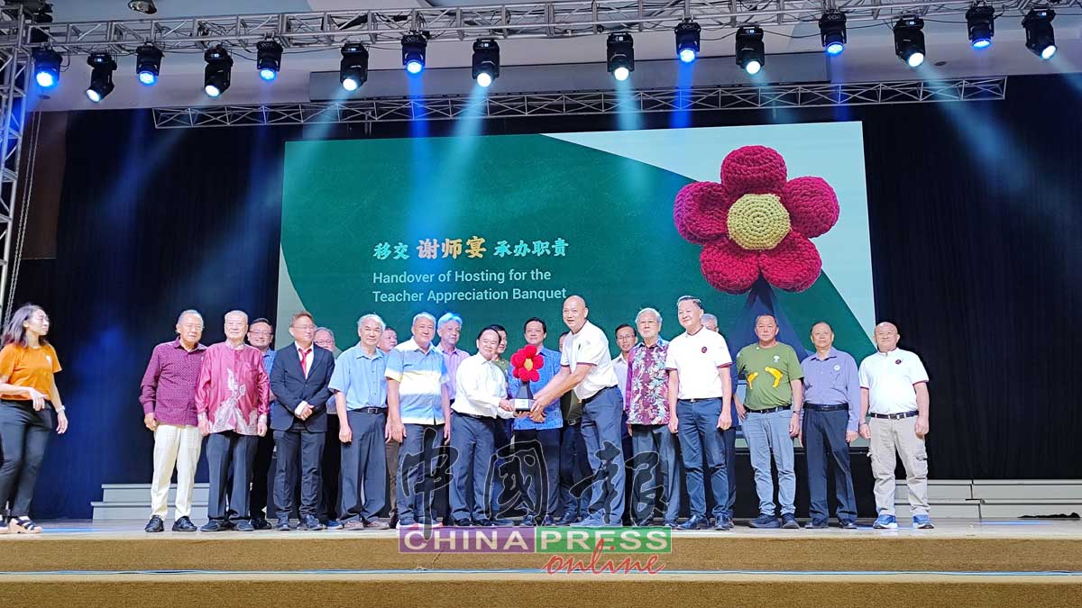 庄俊隆（右6）移交象征谢师宴承办职责的“大红花”给予下一届轮值承办单位柔佛董联会，由陈大锦（左6）接领。曾敏凯（左7）见证。